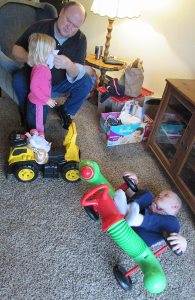 Dad Aaron Campbell, 49, helps daughter Lanaya, 2, while son Ryker, 4, plays in the living room of the family's new apartment.